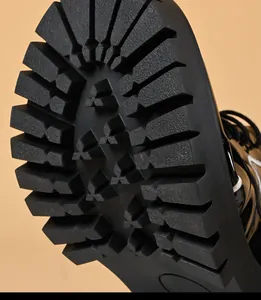 Macro view of the deep tread pattern on a black rubber lug sole for men's platform shoes.