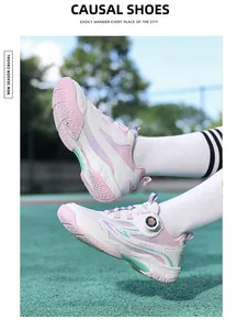 Gros plan de chaussures de sport roses et blanches pour enfants sur un terrain.