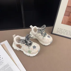 Detailansicht von Kinder-Sneakern mit Blumenmuster, Spitzenschleifen und Mesh-Blumen.