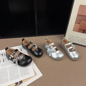 Dettaglio scarpe da principessa per bambine nere e argento con fiocco e perle.