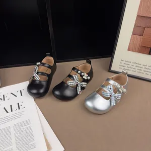 Vista dettagliata di scarpe Mary Jane per bambini in nero e argento con fiocchi.