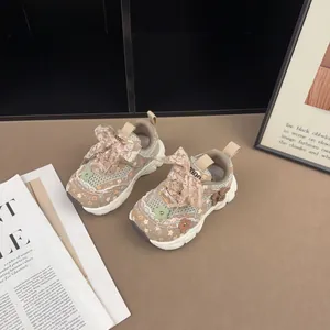 Detail von geblümten Mädchen-Sneakern mit Spitzenschleife und Blumenanhängern im Lifestyle
