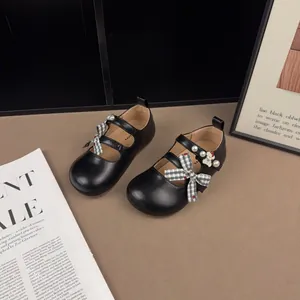 Primo piano di scarpe Mary Jane nere per bambini con fiocchi a quadri e perle