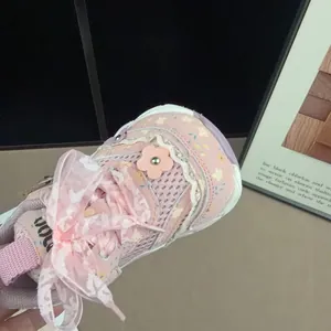 Detailansicht der rosa Mädchen-Sneaker mit Spitzenbesatz und floralem Muster.