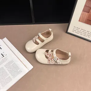 Vista dettagliata di scarpe da principessa color crema per bambini con fiocco e perle