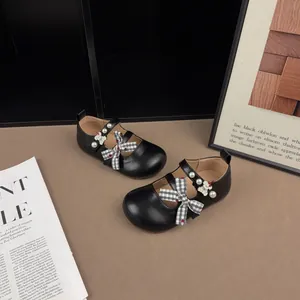Dettaglio scarpe Mary Jane nere per bambini con fiocco e accenti di perle lucide.