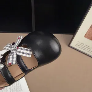 Dettaglio ravvicinato di scarpe Mary Jane nere da bambina con fiocco e perla fine