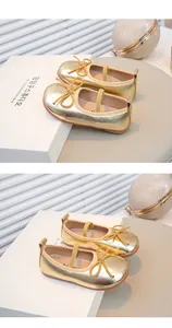 Detailaufnahme der goldenen Mädchenschuhe mit Schleifendekoration und weicher Sohle
