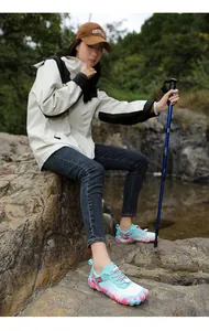 Woman wearing aqua blue hiking shoes for outdoor trekking on rocky terrain near water