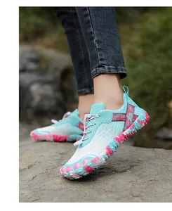Detail of turquoise and pink outdoor hiking shoes with non-slip sole on a rock