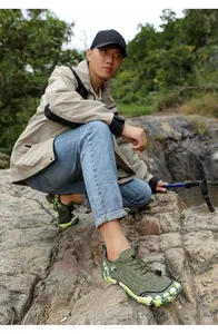 Close-up of green camouflage outdoor hiking shoes worn by a man on rocky terrain