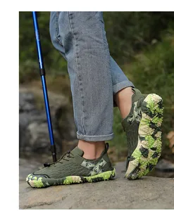 Detailed view of camouflage hiking shoes with anti-slip rubber sole on a rock.