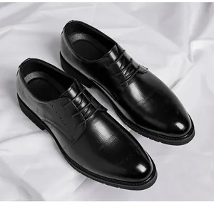 Professional top view of black textured leather men's dress shoes on white silk background