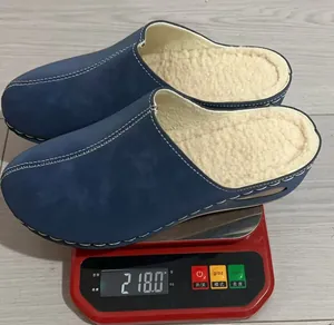 Detail view of a blue fleece-lined slipper on a red scale showing 218g weight
