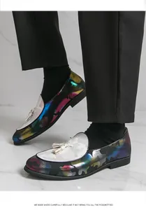 Nahaufnahme von bunten Herren-Loafers mit Tarnmuster, weißen Quasten und schwarzer Hose
