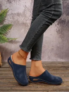 Detailed side view of navy blue wedge fleece-lined mules for women with white stitching.