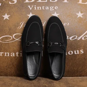 Gedetailleerd bovenaanzicht van zwarte suède loafers met metalen gesp op vintage bodem