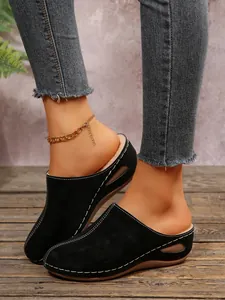 Close-up view of black suede wedge clogs with warm lining and decorative stitching