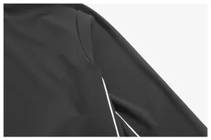 Détail en gros plan montrant la couture d'épaule et le liseré contrastant blanc sur la veste