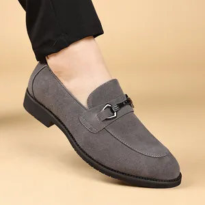 Detailopname van grijze suède herenloafers met een metalen gesp en een puntige neus