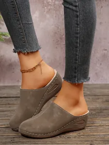 Side detail of grey wedge mules with plush fur lining and decorative white stitching
