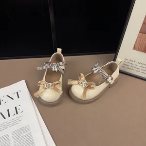Vintage cream children's Mary Jane shoes with decorative bows and pearl rhinestone accents