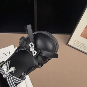 Close-up detail of retro black girls' princess flats featuring elegant bows and pearls