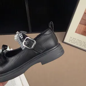 Detailed side view of black children's Mary Jane shoe with bow and pearl accents