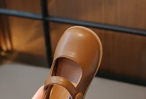 Vue rapprochée de l'orteil rond et du cuir marron texturé d'une chaussure Mary Jane pour fille.