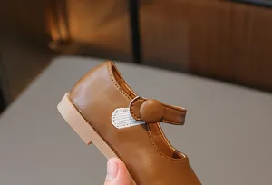 Gros plan d'une chaussure Mary Jane marron pour fille avec bande velcro et bouton.