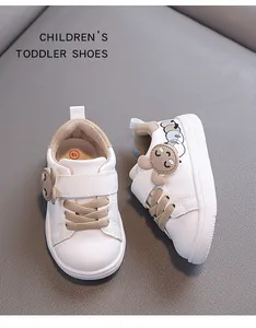 Detail view of white toddler walking shoes with cartoon patches and soft sole