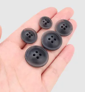Close-up of various sizes of dark grey translucent resin buttons in a palm