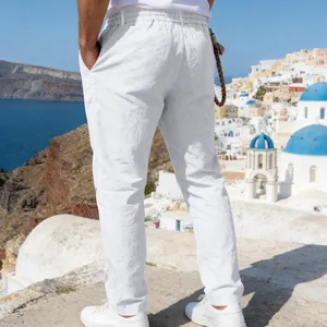 Rear view of men's loose white linen trousers standing in a scenic coastal town