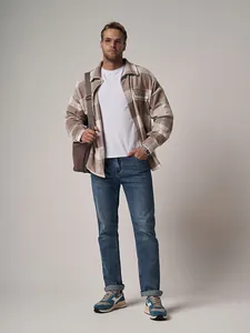 Professional full-length view of men's loose straight-leg blue jeans in a casual autumn outfit.