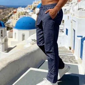 Man wearing navy blue linen trousers in a scenic Mediterranean coastal setting