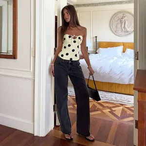 Polka dot strapless corset top with bow detail worn with wide-leg jeans in bedroom