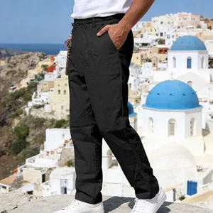 Detailed side view of men's loose black linen casual pants in a scenic coastal setting