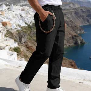 Close-up of black loose linen pants featuring a colorful braided waist accessory.