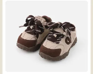 Close-up detail of stylish brown and beige soft-sole baby sneakers with thick patterned laces