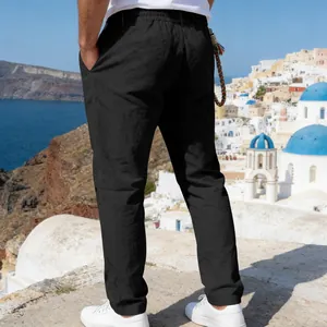 Men's loose black linen pants back view in a scenic coastal Mediterranean setting