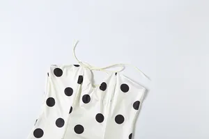 Close-up of a white polka dot tube top featuring a delicate lace-up neckline
