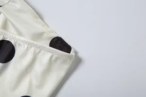 Macro detail showing high-quality stitching on a cream and black polka dot top.