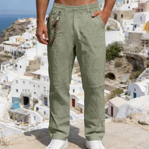 Full view of men's loose sage green linen trousers in a scenic vacation setting