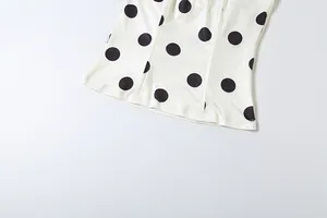 Detail of a chic white tube top with bold black polka dot pattern and fine stitching.