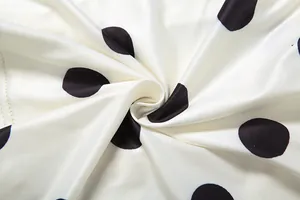 Macro detail of high-quality white fabric with bold black polka dots and silky texture