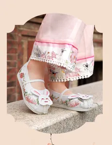 Close-up of girl's Hanfu embroidered shoes with cute rabbit patch and bead details