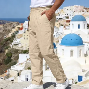 Men's loose linen straight-leg casual pants in beige against a scenic coastal backdrop