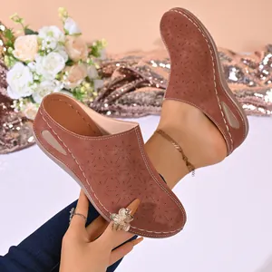 Detail of brown hollow-out wedge clogs featuring laser-cut patterns and white stitching