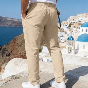 Back view of men's loose khaki linen trousers shown in a scenic coastal setting