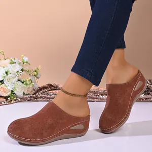 Close-up detail of women's brown hollow-out thick sole clogs worn with denim jeans